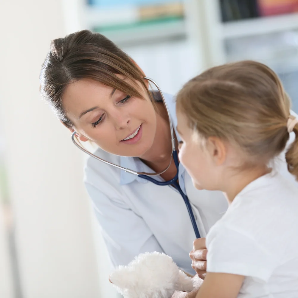 A GP using a stethoscope to examine a child's chest